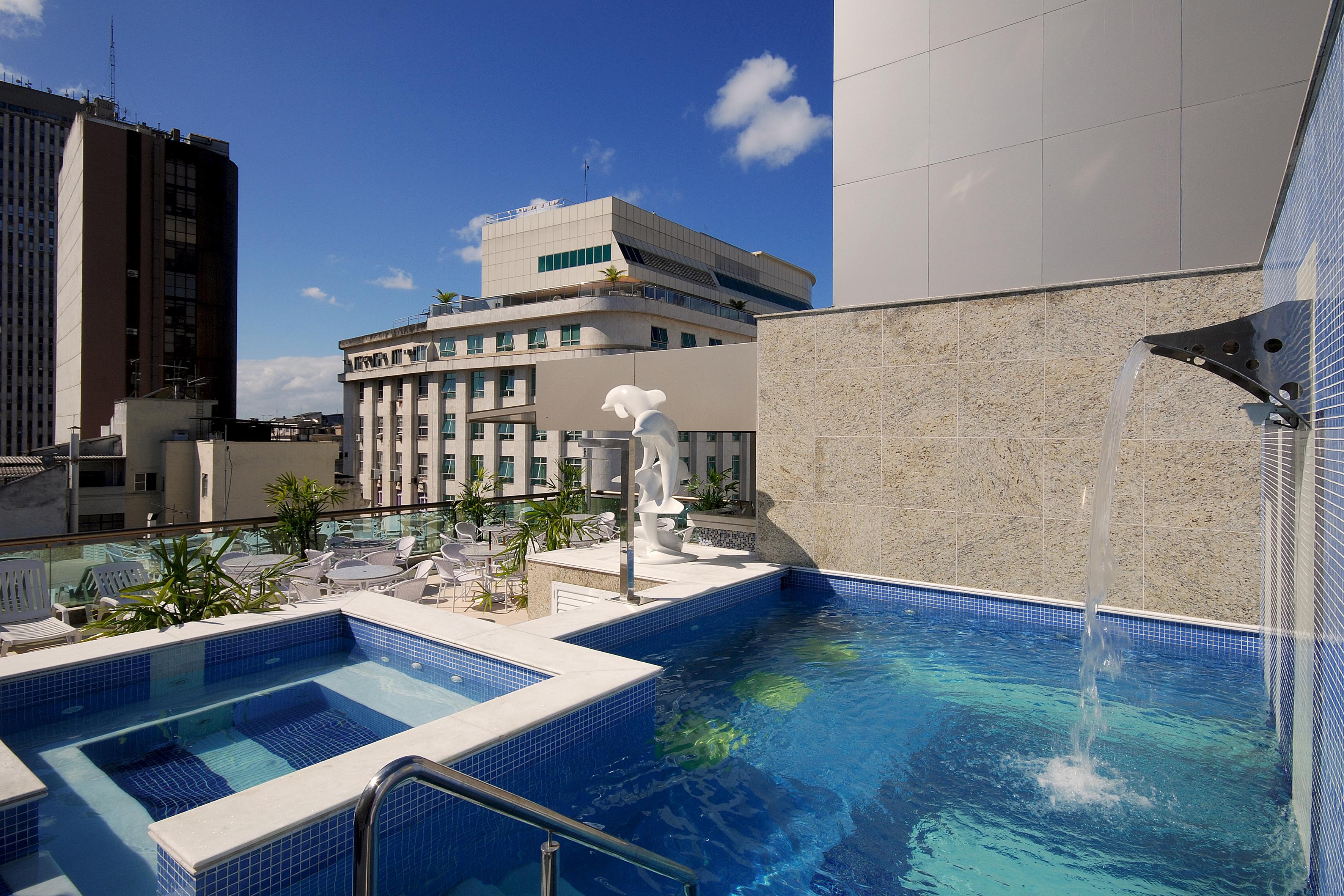 Hotel Atlantico Business Centro Rio de Janeiro Dış mekan fotoğraf The photo shows a rooftop area featuring a swimming pool and a spa. The pool is inviting with a clear blue water, and there appears to be a waterfall feature. Surrounding the pool are areas for relaxation, possibly with sun loungers. In the backgroun